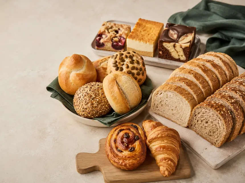 Sortimentsübersicht: Brötchen, geschnittene Brote, Blechkuchen, Nussschnecke und Croissant.